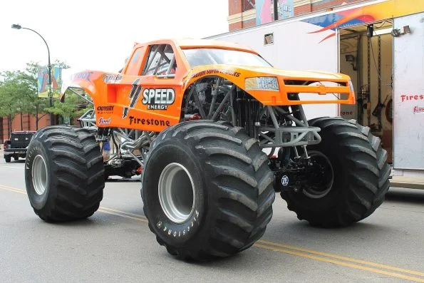 Bob Chandler's Bigfoot 19 monster truck parked on a street, featuring an orange body and Firestone tyres.