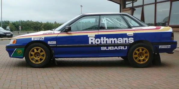 Subaru Legacy RS rally car in the blue, white and gold Rothmans livery, side view, gold wheels
