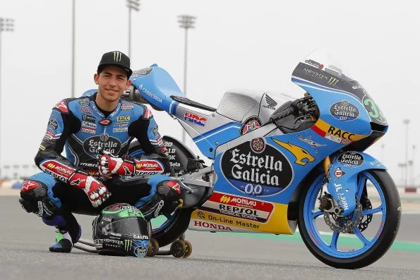 Enea Bastianini crouching beside his blue Estrella Galicia 0,0 Honda Moto3 machine on track at the 2017 Qatar Grand Prix.