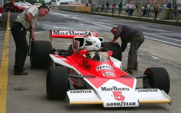 McLaren M23 vintage F1 racing car in Marlboro livery parked in the pit lane during a historic motorsport meeting.