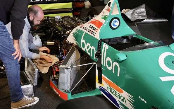 Benetton Renault F1 B186 green racing car with a mechanic working on the engine bay during the 1986 season