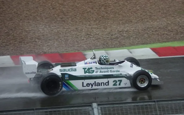 Williams 1980 FW07 racing car in Saudia-Leyland livery driving on a wet track during a Grand Prix weekend