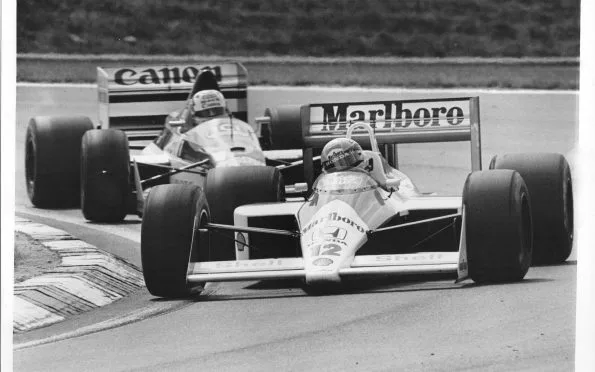 McLaren MP4/4 turbo F1 racing car competing closely alongside a Williams car during the 1988 Hungarian Grand Prix.