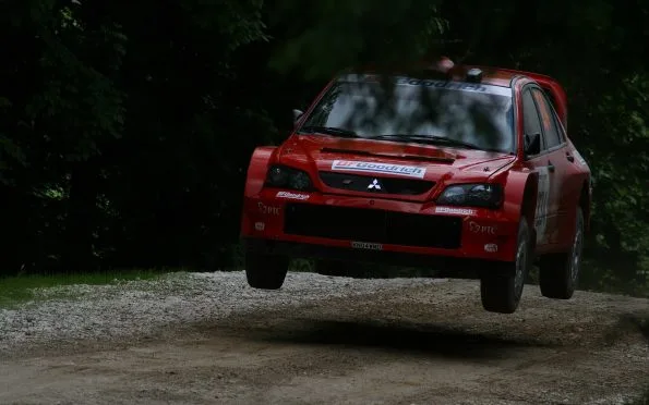 Mitsubishi Ralliart Lancer Evolution rally car airborne on a high-speed gravel stage driven by Tommi Mäkinen.
