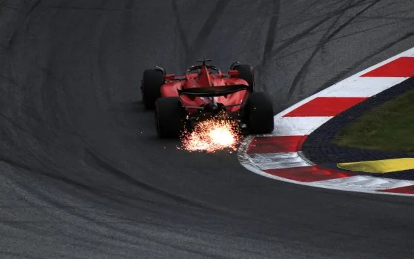 Scuderia Ferrari SF-23 Formula 1 car trailing bright sparks over the kerb, driven by Charles Leclerc at the Austrian Grand Prix