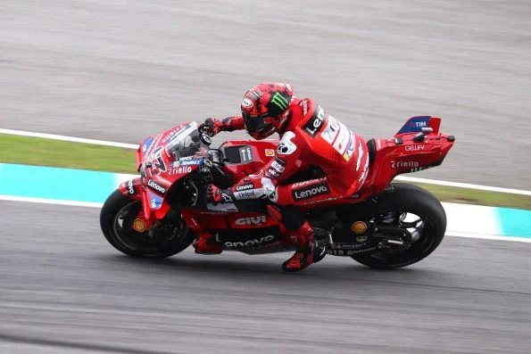 Francesco Bagnaia cranked hard over on the red Ducati Lenovo machine at speed on track.