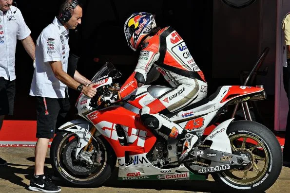 Jack Miller sitting on his number 43 LCR Honda MotoGP machine in pit lane, with team mechanics alongside, during the 2015 season.