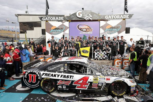 Kevin Harvick's number 4 Jimmy John's Chevrolet covered in confetti in victory lane, with the race team posed behind the car.