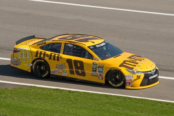 Kyle Busch's yellow M&M's-liveried number 18 Toyota Camry of Joe Gibbs Racing, on track.