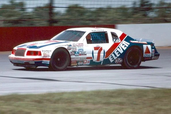 Kyle Petty driving the Wood Brothers' white and red number 7 7-Eleven Ford Thunderbird on track.
