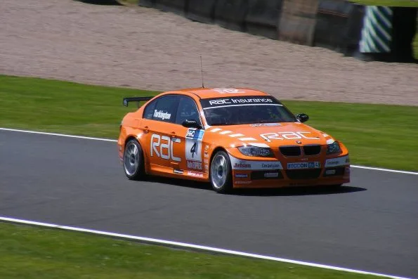 The orange RAC-liveried number 4 BMW 320si of Colin Turkington at Knickerbrook at Oulton Park during the 2009 British Touring Car Championship.