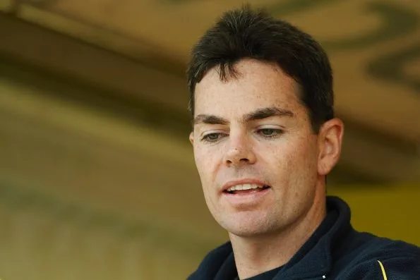 Close-up of Craig Lowndes in 2006, looking down and away from the camera with a slight smile, wearing a dark navy team fleece.