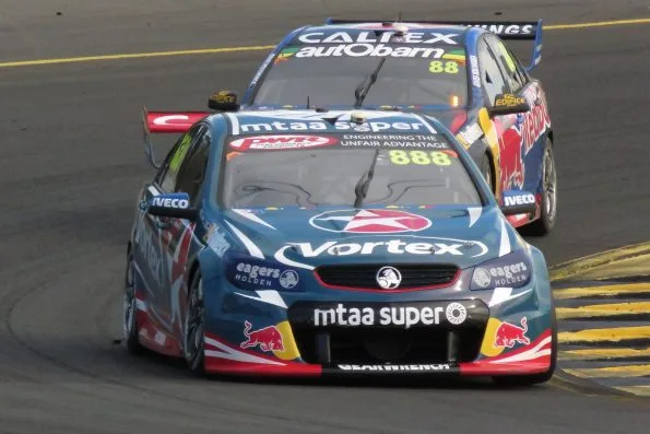 Craig Lowndes's number 888 TeamVortex Holden VF Commodore leading the number 88 Red Bull Caltex Commodore through a corner at Sydney Motorsport Park in 2016.