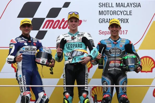 Joan Mir (race winner) in Leopard Racing leathers on the Moto3 podium at the 2017 Malaysian Grand Prix, alongside Jorge Martín and Enea Bastianini.