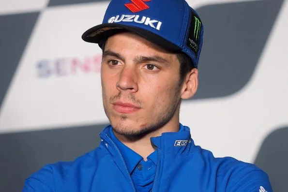 Joan Mir in Team Suzuki Ecstar clothing and a Suzuki cap at a 2021 MotoGP press conference.