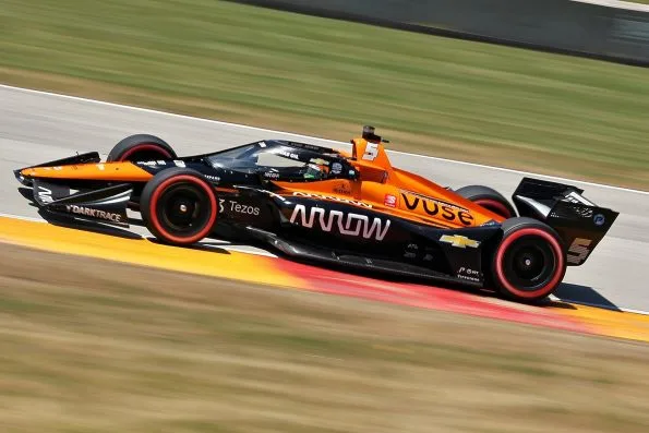 Pato O'Ward's orange and black Arrow McLaren Dallara-Chevrolet, car 5, panned at speed over the kerb at Road America in 2021.