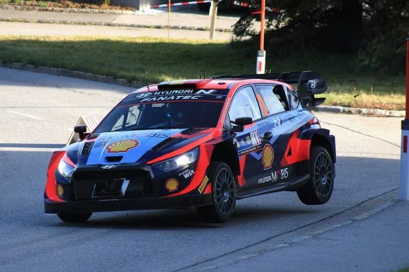 Thierry Neuville's Hyundai i20 N Rally1, car 11, turning in on an asphalt stage at the 2023 Central European Rally, a Belgian flag stripe across the roof and his and Martijn Wydaeghe's names on the side window.